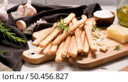 Fresh baked homemade grissini bread sticks in vintage metal grid box with olive oil and rosemary herbs over kitchen counter top. Стоковое фото, агентство Ingram Publishing / Фотобанк Лори