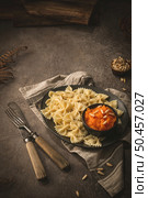 Farfalle pasta in a ceramic plate with pumpkin puree and pine nuts in a small ceramic bowl on a dark stone kitchen counter top. Стоковое фото, агентство Ingram Publishing / Фотобанк Лори