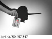 Vote fraud and Election dishonest voting or rigging elections and voter deception crime as a hand with a ballot casting a shadow of a liar or Lieing as an illegal electoral activity in a 3D illustration style. Стоковое фото, агентство Ingram Publishing / Фотобанк Лори