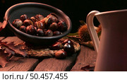 Roasted chestnuts on a rustic wooden table with autumn leaves in the background. Стоковое фото, агентство Ingram Publishing / Фотобанк Лори