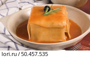 Traditional Portuguese snack food. Francesinha sandwich of bread, cheese, pork, ham, sausages, with tomato beer sauce and French fries. With beer and potatoes. On table. Стоковое фото, агентство Ingram Publishing / Фотобанк Лори