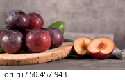 Delicious red plums in a cork plate on kitchen countertop. Стоковое фото, агентство Ingram Publishing / Фотобанк Лори