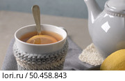 Cup of hot tea with lemon dressed in knitted warm winter scarf on wooden tabletop. Стоковое фото, агентство Ingram Publishing / Фотобанк Лори