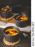 Creme brulee. Bowls with French vanilla cream dessert with caramelised sugar on top, spoons, dark rustic table. Стоковое фото, агентство Ingram Publishing / Фотобанк Лори