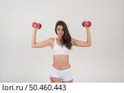 Portrait of young beautiful woman making physical exercises with dumbbells. Стоковое фото, агентство Ingram Publishing / Фотобанк Лори
