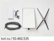 KYIV, UKRAINE - JANUARY 24, 2023: Basic Starlink kit, antenna, wi-fi router, base and cables, top view on white background. Редакционное фото, агентство Ingram Publishing / Фотобанк Лори