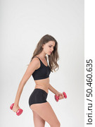 Portrait of young beautiful woman making physical exercises with dumbbells. Стоковое фото, агентство Ingram Publishing / Фотобанк Лори