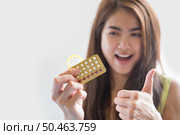 Young woman holding condom and contraceptive pills prevent pregnancy. Стоковое фото, агентство Ingram Publishing / Фотобанк Лори