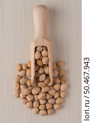 Top view of wooden scoop with chickpeas against beige vinyl background. Стоковое фото, агентство Ingram Publishing / Фотобанк Лори