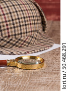 Deerstalker or Sherlock Hat and magnifying glass on Old Wooden table. Стоковое фото, агентство Ingram Publishing / Фотобанк Лори