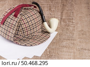 Deerstalker or Sherlock Hat and Tobacco pipe on Old Wooden table. Стоковое фото, агентство Ingram Publishing / Фотобанк Лори