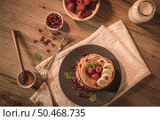 Pancakes with raspberries, banana slices, pomegranate seeds and honey on wooden vintage table. Стоковое фото, агентство Ingram Publishing / Фотобанк Лори