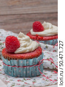 Red cupcakes with cream cheese frosting and raspberries  on white wooden table. Стоковое фото, агентство Ingram Publishing / Фотобанк Лори
