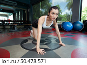 Young women warms up before exercising by pushing the floor and bending his knees in Gym. Стоковое фото, агентство Ingram Publishing / Фотобанк Лори