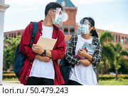Male and female students wear masks and stand in front of the university. Стоковое фото, агентство Ingram Publishing / Фотобанк Лори