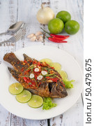 Fried tilapia with chili sauce, lemon salad and garlic on a plate on a white wooden table. Стоковое фото, агентство Ingram Publishing / Фотобанк Лори