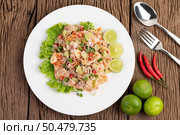 Spicy pork salad with galangal, lemon, chilli, garlic and put in a salad on a white plate, On wooden Table. Стоковое фото, агентство Ingram Publishing / Фотобанк Лори