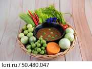 Chili paste paste in a bowl with eggplant, carrots, chili, cucumbers in a basket on wood table. Стоковое фото, агентство Ingram Publishing / Фотобанк Лори