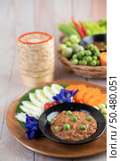 Chili paste paste in a bowl with eggplant, carrots, chili, cucumbers in a basket on wood table. Стоковое фото, агентство Ingram Publishing / Фотобанк Лори