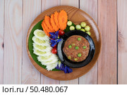 Chili paste paste in a bowl with eggplant, carrots, chili, cucumbers in a basket on wood table. Стоковое фото, агентство Ingram Publishing / Фотобанк Лори