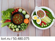 Chili paste paste in a bowl with eggplant, carrots, chili, cucumbers in a basket on wood table. Стоковое фото, агентство Ingram Publishing / Фотобанк Лори