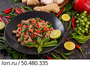 Stir-fried pork basil on banana leaves in a black dish. Thai food. Стоковое фото, агентство Ingram Publishing / Фотобанк Лори