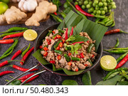 Stir-fried pork basil on banana leaves in a frying pan. Thai food. Стоковое фото, агентство Ingram Publishing / Фотобанк Лори