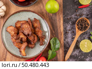 Pork cutlet in a white plate with pepper seeds, kaffir lime leaves, lemons, chilies, garlic on black cement. Стоковое фото, агентство Ingram Publishing / Фотобанк Лори