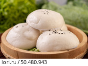 Steamed buns in a wooden dish on a wooden grill. Selective focus. Стоковое фото, агентство Ingram Publishing / Фотобанк Лори