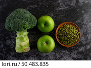 Broccoli, Apple, and Mung bean on a black cement floor background. Стоковое фото, агентство Ingram Publishing / Фотобанк Лори