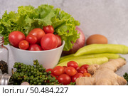 Lettuce and tomatoes in a white cup with sliced ??onions and fresh peppers on the cement floor. Стоковое фото, агентство Ingram Publishing / Фотобанк Лори