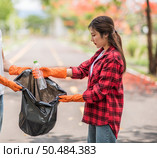 Men and women helped to collect garbage in a black bag. Стоковое фото, агентство Ingram Publishing / Фотобанк Лори