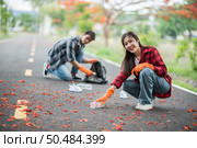 Men and women helped to collect garbage in a black bag. Стоковое фото, агентство Ingram Publishing / Фотобанк Лори