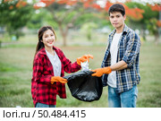 Men and women helped to collect garbage in a black bag. Стоковое фото, агентство Ingram Publishing / Фотобанк Лори