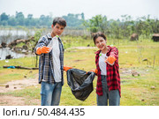 Men and women helped to collect garbage in a black bag. Стоковое фото, агентство Ingram Publishing / Фотобанк Лори