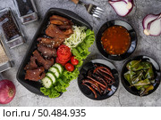 Fried pork topped with sesame, complete with tomatoes, cucumbers, cabbage, and lettuce placed in a black dish. Стоковое фото, агентство Ingram Publishing / Фотобанк Лори