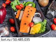 Raw salmon fillets, pepper, kiwi, pineapples, and rosemary onto a plate and black cement floor. Стоковое фото, агентство Ingram Publishing / Фотобанк Лори