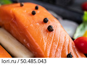 Raw salmon fillets, pepper, kiwi, pineapples, and rosemary onto a plate and black cement floor. Стоковое фото, агентство Ingram Publishing / Фотобанк Лори