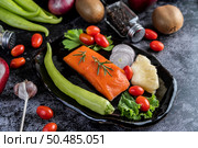 Raw salmon fillets, pepper, kiwi, pineapples, and rosemary onto a plate and black cement floor. Стоковое фото, агентство Ingram Publishing / Фотобанк Лори