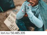 a man sitting beggars with homeless please help message. Selective focus. Стоковое фото, агентство Ingram Publishing / Фотобанк Лори