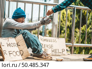 The man sitting begging on an overpass with messages homeless people please help and work well with food. Стоковое фото, агентство Ingram Publishing / Фотобанк Лори