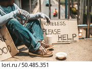 The man sitting begging on an overpass with messages homeless people please help and work well with food. Стоковое фото, агентство Ingram Publishing / Фотобанк Лори