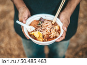 The beggar stands to hold with noodles in a foam cup complete with chopsticks and spoons. Стоковое фото, агентство Ingram Publishing / Фотобанк Лори