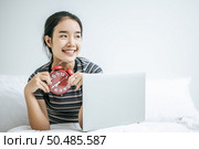 That woman sat on the bed, held the alarm clock and placed the laptop. Стоковое фото, агентство Ingram Publishing / Фотобанк Лори