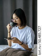 There was a girl sitting and drinking coffee in the bedroom and a pillow on her legs. Стоковое фото, агентство Ingram Publishing / Фотобанк Лори