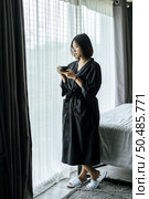 The woman wore a black robe near the window and drank coffee in the bedroom. Стоковое фото, агентство Ingram Publishing / Фотобанк Лори