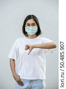 The woman is wearing a mask and pointing her thumb down. Стоковое фото, агентство Ingram Publishing / Фотобанк Лори