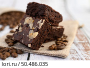 Chocolate brownies on sackcloth and coffee beans on a wooden table. Selective focus. Стоковое фото, агентство Ingram Publishing / Фотобанк Лори