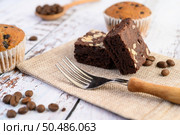 Chocolate brownies on sackcloth and coffee beans, fork on a wooden table. Selective focus. Стоковое фото, агентство Ingram Publishing / Фотобанк Лори