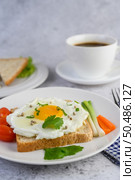 A fried egg laying on a toast, topped with pepper seeds with carrots and spring onions. Стоковое фото, агентство Ingram Publishing / Фотобанк Лори